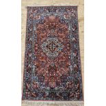 A Persian style rug, possibly Indian, with a busy pale red field and bird motif to border 174cm x