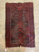 An old hand knotted Baluch rug, the red ground with pole medallion and bordered 136cm x 86cm