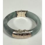 A Chinese white metal mounted circular grey/ celedon coloured Jadite bangle with engraved water lily
