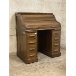 An Edwardian oak roll top desk, the serpentine tambour front with key and lock escutcheon stamped