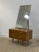 Stag, a mid century light oak veneered dressing chest, with swing mirror above two drawers, raised