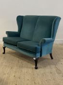 Parker Knoll, a wingback two seat sofa, upholstered in teal velvet, raised on cabriole supports
