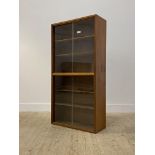 A mid century teak two height bookcase by Cumbrae furniture, four sliding glazed doors enclosing