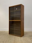 A mid century teak two height bookcase by Cumbrae furniture, four sliding glazed doors enclosing
