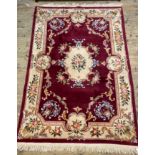 A Chinese washed wool rug, with a claret red ground, ivory spandrels and border 186cm x 295cm