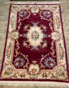 A Chinese washed wool rug, with a claret red ground, ivory spandrels and border 186cm x 295cm