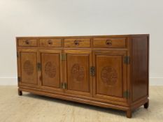 A Chinese hardwood sideboard, the panelled top over four drawers and four carved panel doors, raised
