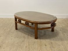 A Chinese hardwood oval coffee table, the plate glass top over open fret caved straight scroll