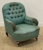 An early 20th century armchair, upholstered in buttoned teal damask, raised on turned supports and