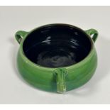 A pottery green glazed fruit bowl in the French nouveau style with three scroll handles to side (