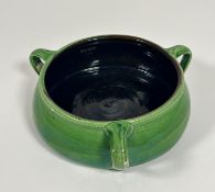 A pottery green glazed fruit bowl in the French nouveau style with three scroll handles to side (