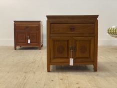 A pair of Chinese hardwood bedside cabinets, each with a panelled top over drawer and cupboard