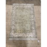 A hand knotted Persian style rug, the pale green ground within an ivory border decorated with
