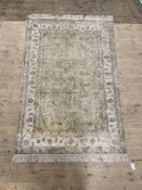 A hand knotted Persian style rug, the pale green ground within an ivory border decorated with