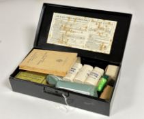 A WWII Air Raid Precautions First Aid Kit by Boots, black metal tin containing pressing bandages,