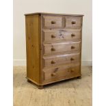 A polished pine chest fitted with two short and three long drawers, raised on compressed bun