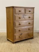 A polished pine chest fitted with two short and three long drawers, raised on compressed bun