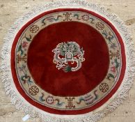 A Chinese washed wool centre rug, the red field with dragon medallion and shou motif to ivory border