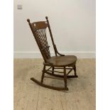 A late 19th century oak rocking chair, with spindle back over saddle seat, raised on turned supports