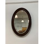 An early 20th century walnut framed oval wall hanging mirror with bevelled plate 85cm x 60cm