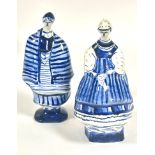 A pair of Polish Warsaw pottery figures dressed in traditional costume decorated with blue and white