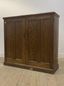 An early to mid 20th century oak cupboard, two panelled doors enclosing three shelves to interior,
