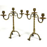 A pair of Edwardian Arts and Crafts brass three branch candelabra raised on spiral tapered columns