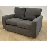 A contemporary two seat sofa, upholstered in grey fabric, raised on beech block supports H74cm,