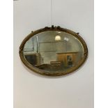 An early 20th century gilt composition framed oval wall hanging mirror, with reeded and floral