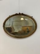 An early 20th century gilt composition framed oval wall hanging mirror, with reeded and floral