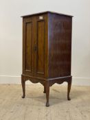 An early 20th century mahogany music cabinet, with two panelled doors enclosing shelves, raised on