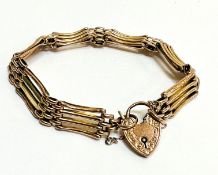 A yellow metal gate link bracelet with 9ct gold engraved heart shaped padlock and safety chain, (