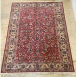 A Persian style carpet or rug, the fuchsia field centred by herati, and with lotus head motif, the