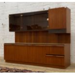 A 1970s mid century teak wall display unit, the floating superstructure with smoked glass cabinets