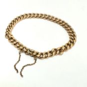An Edwardian yellow metal kerb link bracelet with clip fastening and safety chain (a/f) small