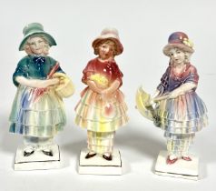 Katzhutte, a group of three small figures of girls with bonnets, one holding a basket, one holding a