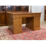 A late 19th / early 20th century oak twin pedestal desk, the top inset with tooled skiver, above one