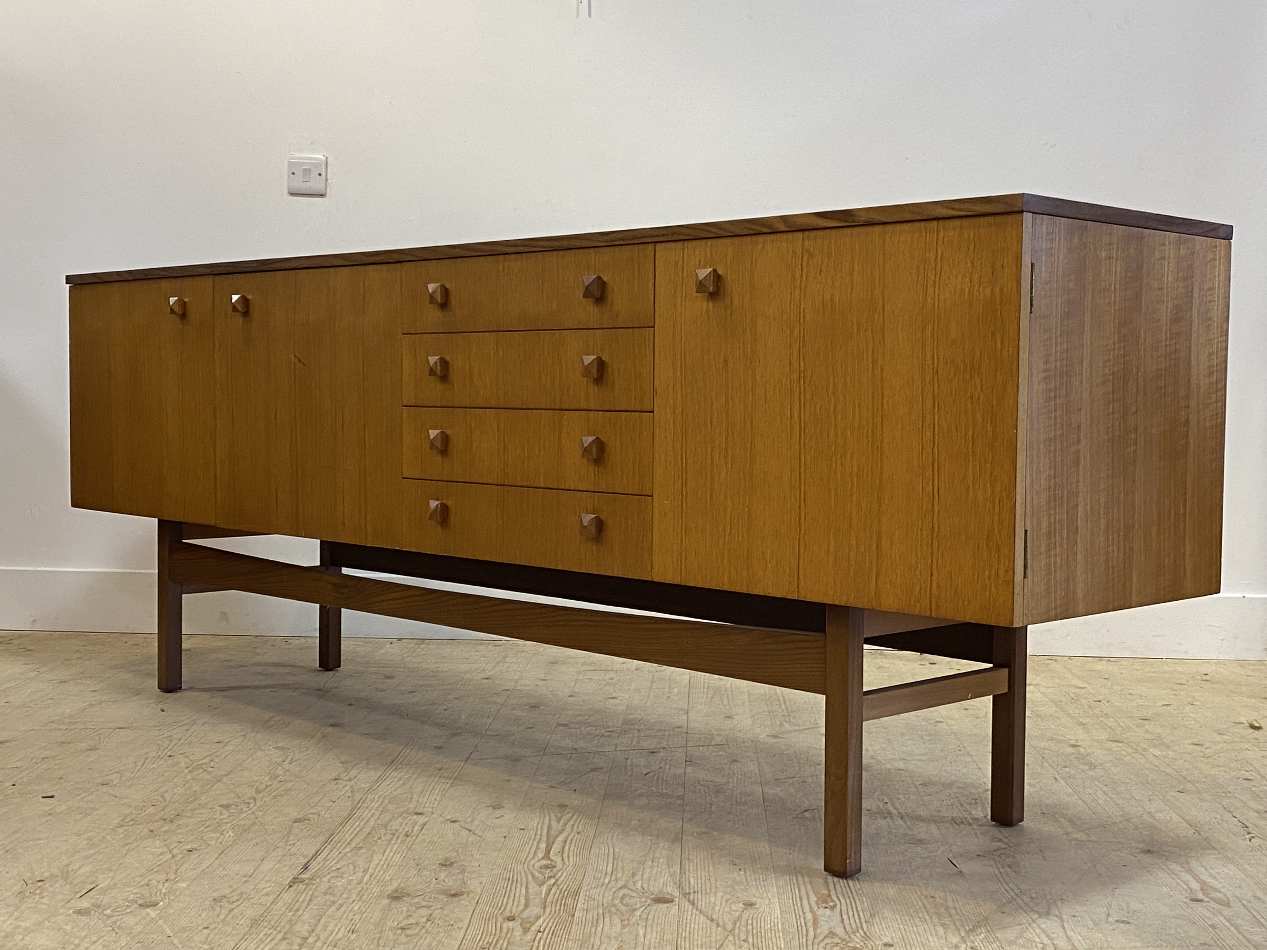 A mid century teak sideboard in the Danish style, the centre fitted with four drawers and a fall