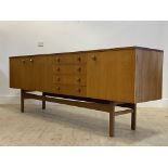 A mid century teak sideboard in the Danish style, the centre fitted with four drawers and a fall