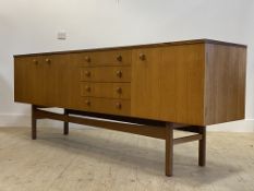 A mid century teak sideboard in the Danish style, the centre fitted with four drawers and a fall