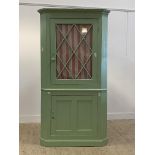 A 19th century painted pine two part corner cabinet, with astragal glazed door enclosing two