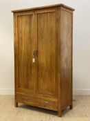 A Contemporary oak wardrobe, the twin panelled doors opening to an interior fitted for hanging,