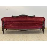 A Victorian carved walnut framed boudoir sofa of ovoid outline, well upholstered in red velvet,