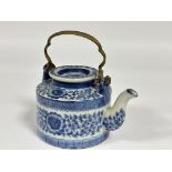 A modern Chinese style porcelain tea pot with brass handle to top decorated with blue and white leaf