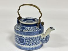 A modern Chinese style porcelain tea pot with brass handle to top decorated with blue and white leaf