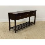 A stained hardwood console table, fitted with three drawers over square tapered supports united by a