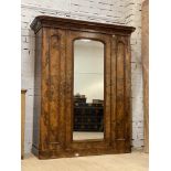 A well figured Victorian walnut wardrbe, the projecting cornice above a centre mirrored door,