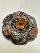 A white metal Scottish style shaped brooch set central amber faceted glass style stone enclosed with