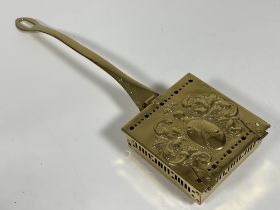 A brass square shaped chestnut roaster with chased Coat of Arms enclosed within a scrolling leaf