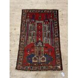 An old Baluchi rug, the red ground with mihrab, within a geometric border 130cm x 83cm